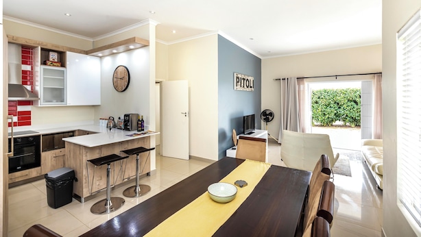 A modern kitchen with a dining area, a TV, and a sign that reads "PITOLI". - Modern Executive Unit (East London)