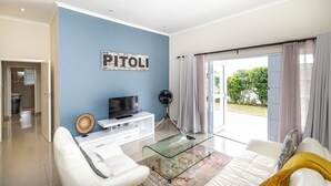 A modern living room with a television, white sofa, and a glass coffee table. - Modern Executive Unit (East London)