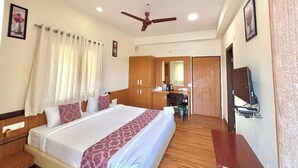 A hotel room with a large bed, wooden wardrobe, desk, and a television on the wall. - Hotel Kailas Residency By Knight Hotel (Chhatrapati Sambhajinagar)