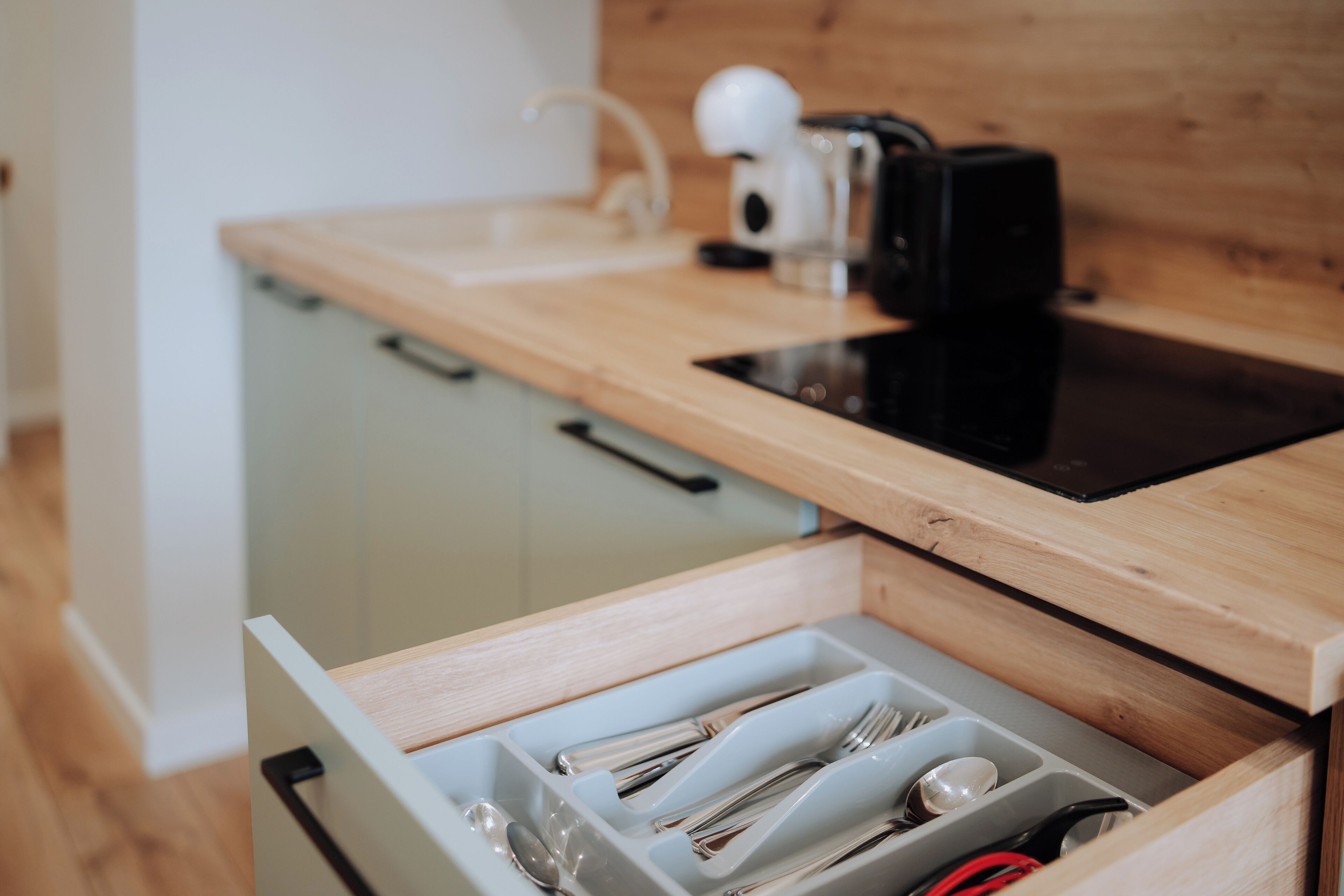 A kitchen drawer with utensils and a coffee maker.