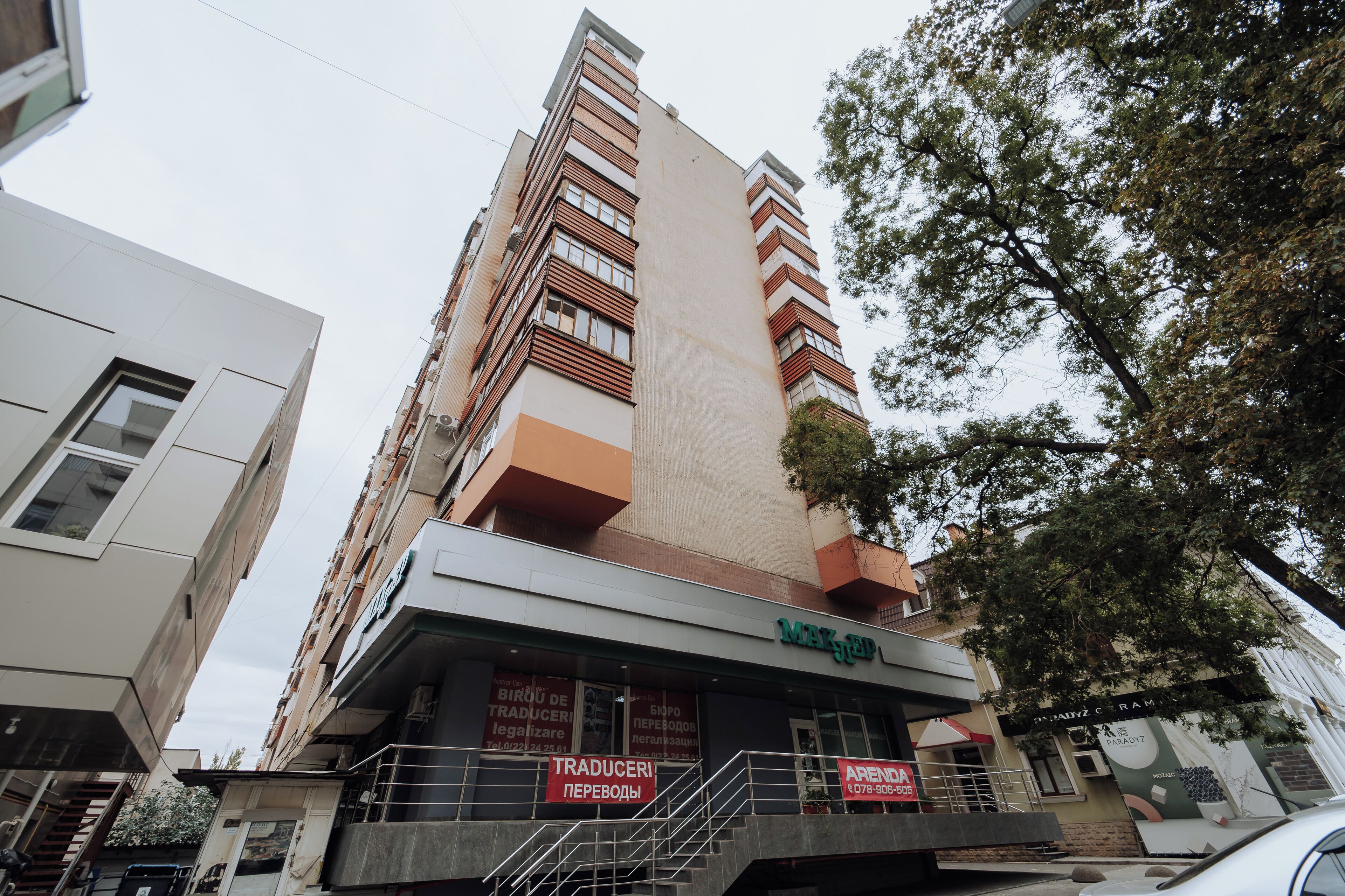 Un immeuble à plusieurs étages doté d’une architecture moderne, avec une entrée imposante, un escalier et une enseigne indiquant « Traduceri Perevodi ».