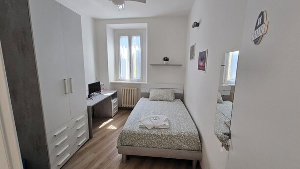Een slaapkamer met een bed, een bureau, een kledingkast en een raam.