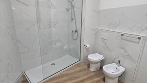 Een moderne badkamer met een glazen douchecabine, een toilet en een douchewc.