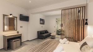 A modern hotel room with a large bed, a desk with a mirror, a sofa, and a TV mounted on the wall. - Lumior Villas Lux essence by 'elite' (Zakynthos)