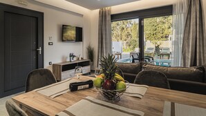 A modern living room with a wooden dining table, a bowl of fruit, and a view of a pool and outdoor seating. - Lumior Villas Lux essence by 'elite' (Zakynthos)