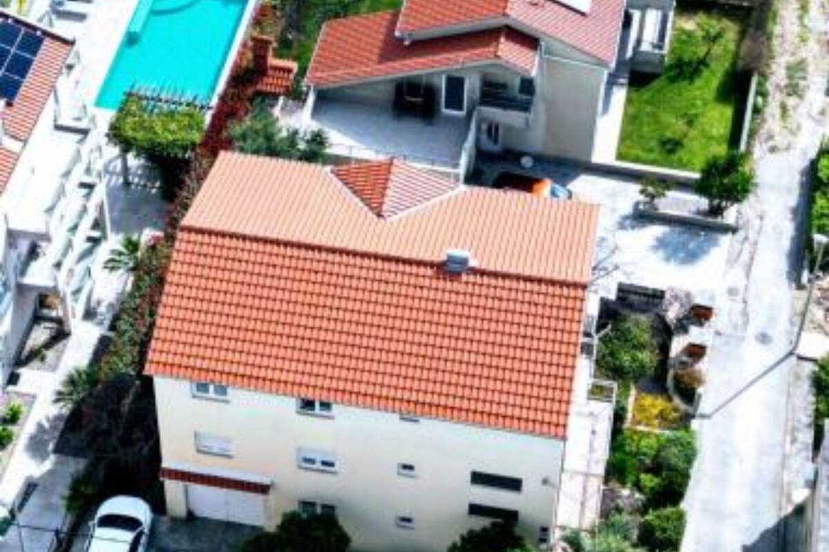 Um edifício residencial com telhado de telhas vermelhas, piscina e jardim.