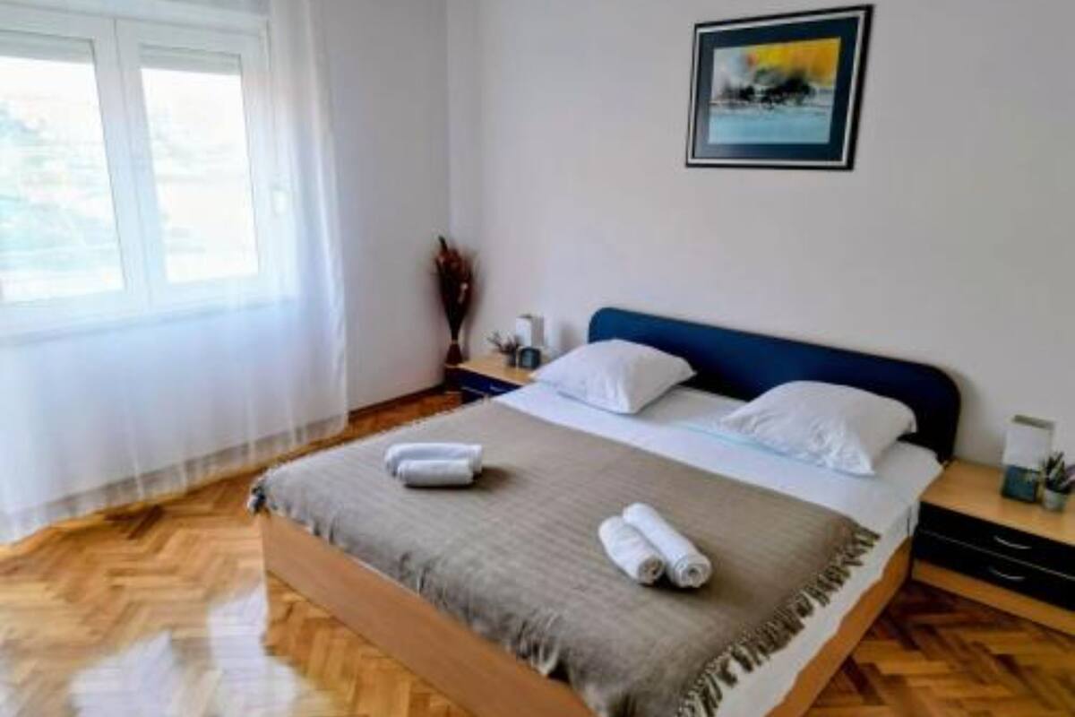 Quarto com cama, janela, quadro e piso de madeira.