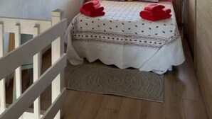 A bedroom with a bed, a window with blinds, a white air conditioning unit, and a wooden floor. - Pretty T2 with garden (Pérols)
