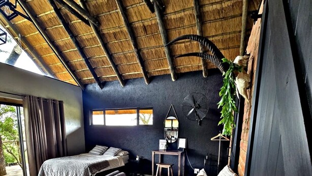 Una habitación con cama, una mesita, un ventilador y una ventana.