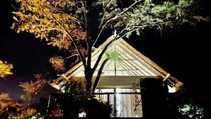Un edificio tradicional japonés con techo de paja, rodeado de árboles.