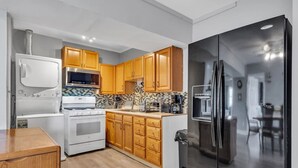 Une cuisine moderne avec des meubles en bois, un réfrigérateur en acier inoxydable, une cuisinière blanche et un four à micro-ondes.