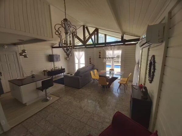 Tilava olohuone, jossa on sohva, ruokapöytä ja tuoleja. Keittiöalueella on työtaso ja televisio.