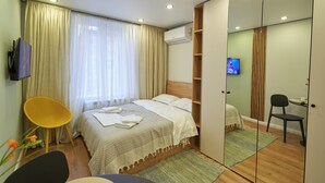 Moderni hotellihuone, jossa on sänky, työpöytä, tuoli ja televisio.