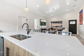 A modern kitchen with a large island, built-in appliances, and a dining area with a view.
