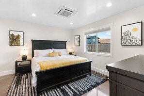 A bedroom with a bed, bedside tables, a window, and artwork on the walls.