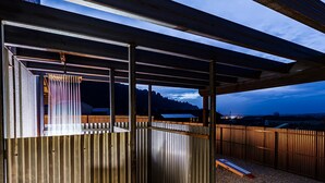 Un espace extérieur abrité, doté d’une clôture en métal, d’un banc en bois et offrant une vue sur les montagnes lointaines.