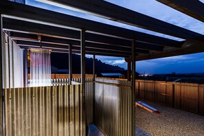 Un espacio al aire libre cubierto con una cerca de metal, un banco de madera y vistas a montañas distantes.