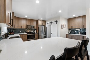 A modern kitchen with wooden cabinets, stainless steel appliances, and a white marble countertop.