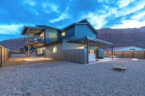 A modern house with a covered patio, a balcony, and a view of the mountains.