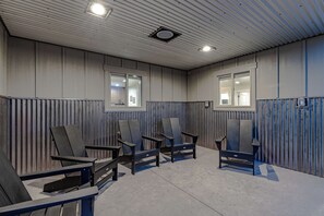 Um quarto com quatro cadeiras dispostas em semicírculo, uma parede de madeira com ripas verticais e duas janelas com persianas.
