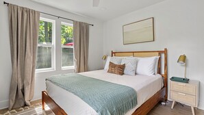 A bedroom with a wooden bed, a bedside table with a lamp, and a view of the outdoors through a window. - 2027 OPEN! (Unit B) Lakeside Home Close To Private Association Beach! (Lakeside)