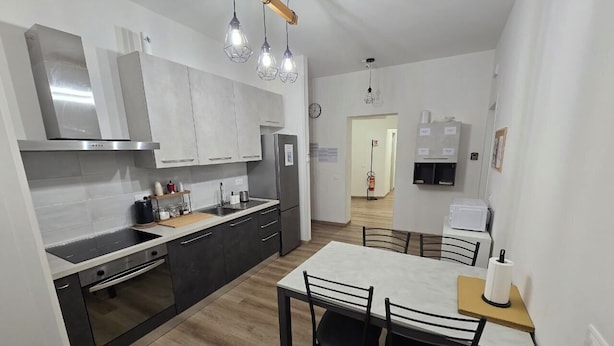 A modern kitchen with a dining area, featuring stainless steel appliances, a wooden countertop, and pendant lighting. - DANITO ROOMS 3 (Ancona)