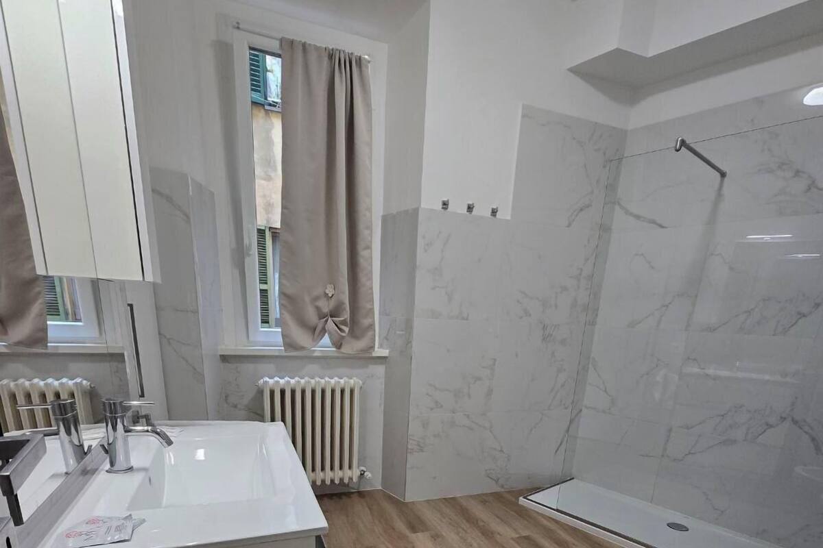 A modern bathroom with a wooden floor, a white sink, a toilet, and a shower area.