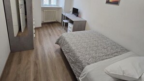 A bedroom with a bed, a desk, a chair, a radiator, a window, and a ceiling fan. - DANITO ROOMS 3 (Ancona)
