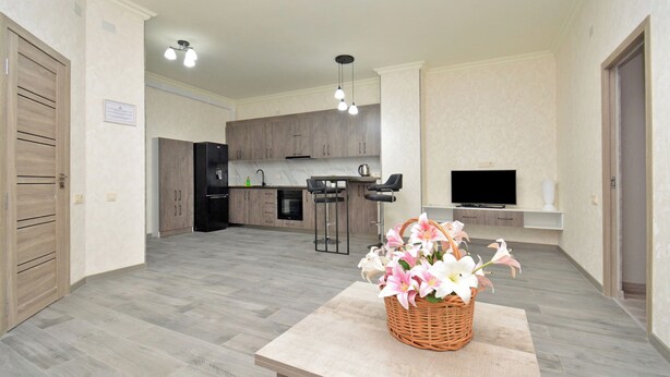 A modern kitchen with wooden cabinets, a central island, and a TV mounted above it.