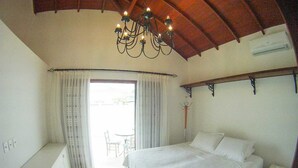 Une chambre à coucher avec un grand lit, un lustre, une fenêtre avec des rideaux et une petite table.