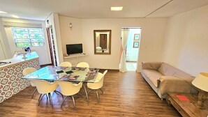Un salon comprenant une table à manger avec un plateau en verre, un canapé et un téléviseur.
