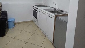 A compact kitchen with white cabinets, a stove, a sink, and a dishwasher. - Tirent Apartment - Your Beach Home in Vlorë (Vlore)