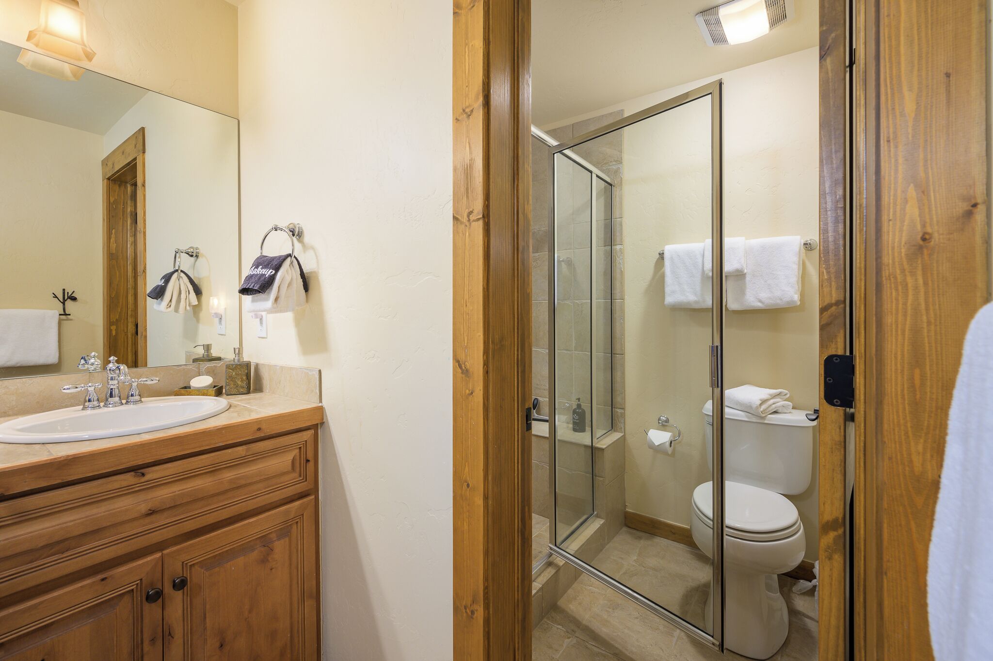 Une salle de bain avec un meuble-lavabo en bois, une cabine de douche en verre et des toilettes.