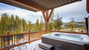 Une terrasse en bois avec un jacuzzi, deux chaises et une table.