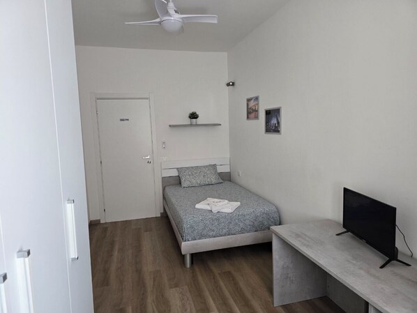 A bedroom with a bed, a desk, a television, a ceiling fan, and a door. - DA.NI.TO. ROOMS 4 (Ancona)