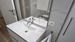 Une salle de bain moderne avec un lavabo blanc, un miroir et un porte-serviettes.
