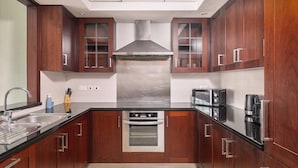 Une cuisine moderne avec des meubles en bois, des appareils électroménagers en acier inoxydable et une hotte aspirante centrale.