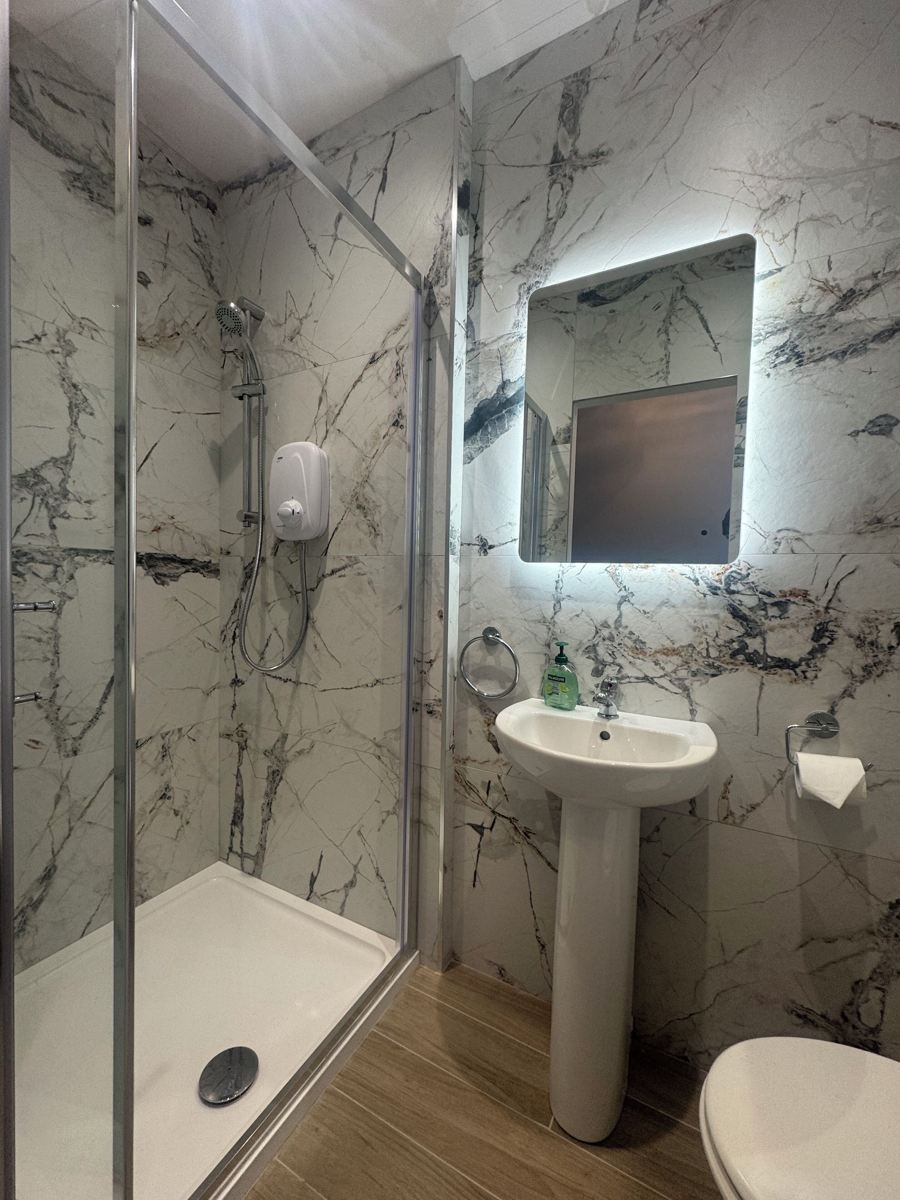 Et badeværelse med bruser, vask og toilet.