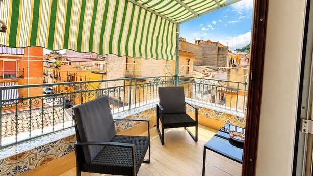 A balcony with two chairs, a small table, and a striped awning. - B&B Le Venere Rooms (Castellammare del Golfo)