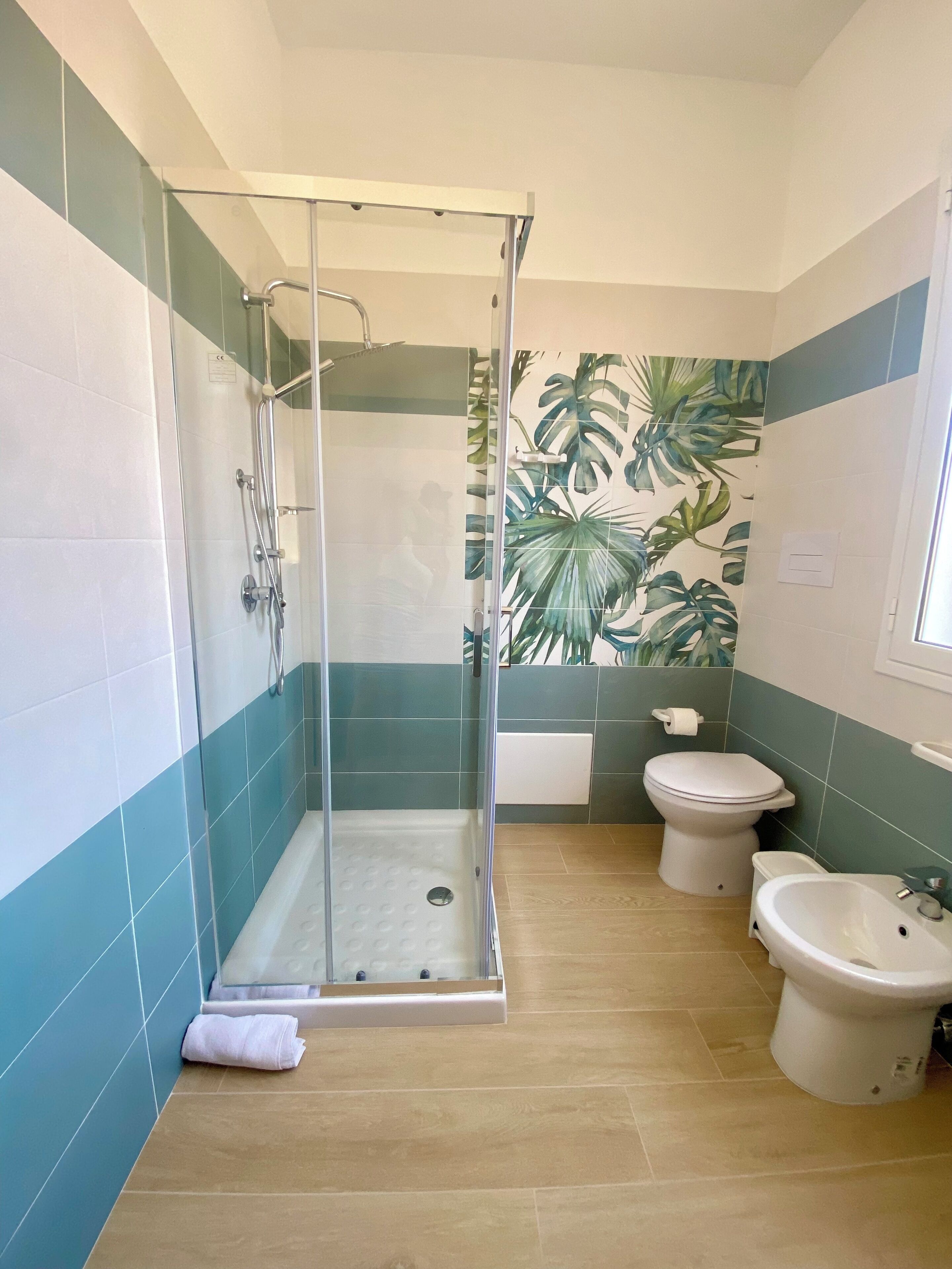 A bathroom with a glass-enclosed shower, a toilet, and a bidet.