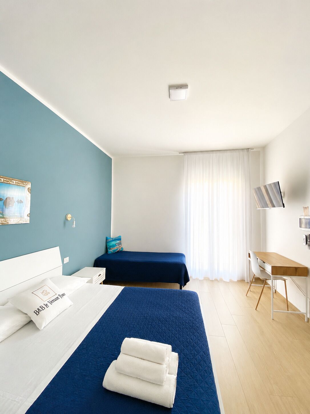 A hotel room with a bed, a desk, and a chair.