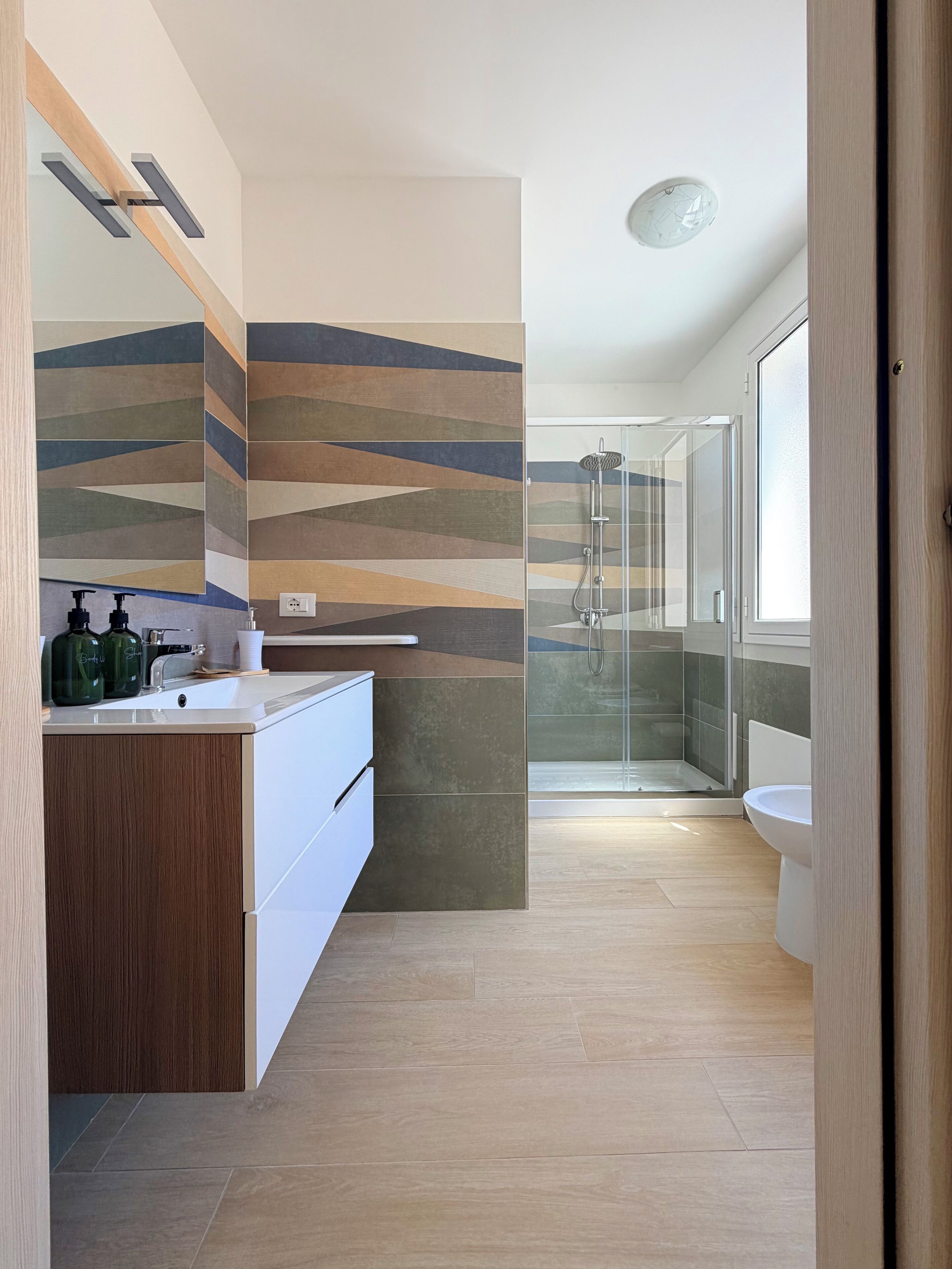 A modern bathroom with a shower, a sink with a mirror, and a toilet.