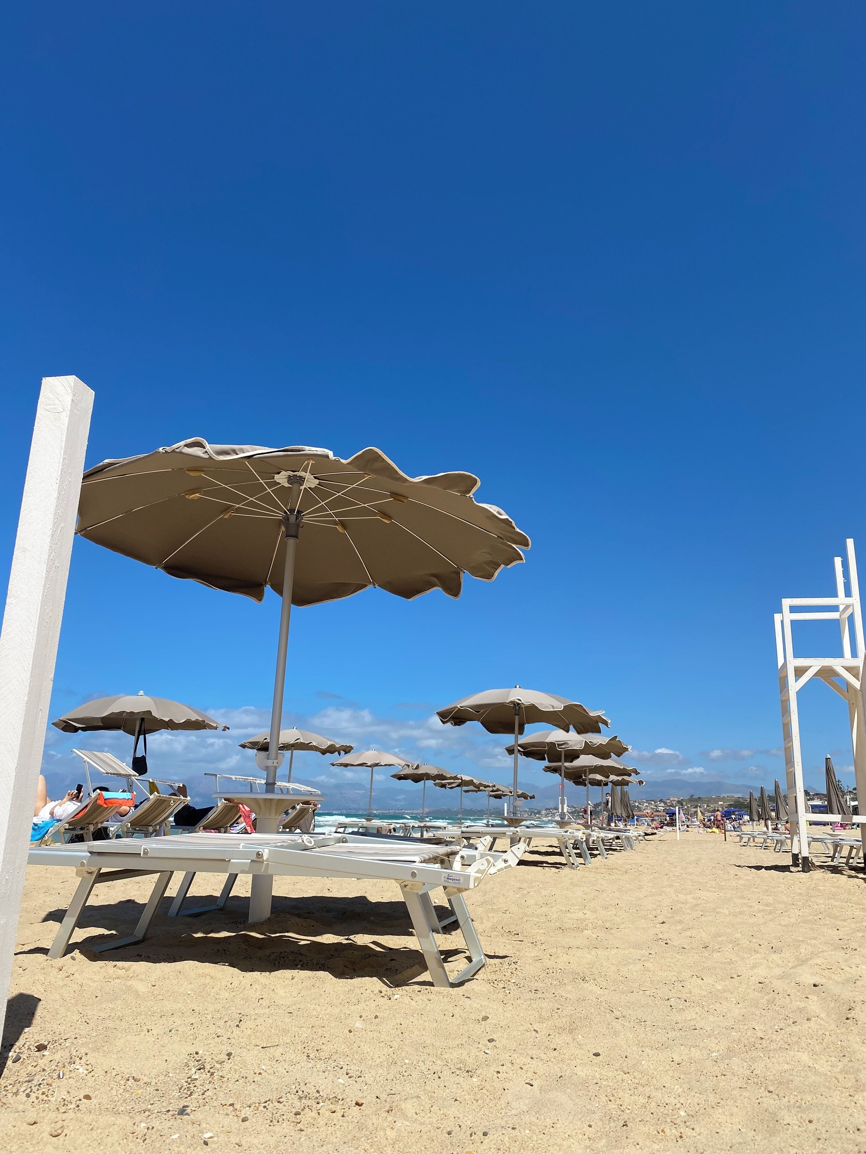 A beach with rows of sun loungers and beach umbrellas.