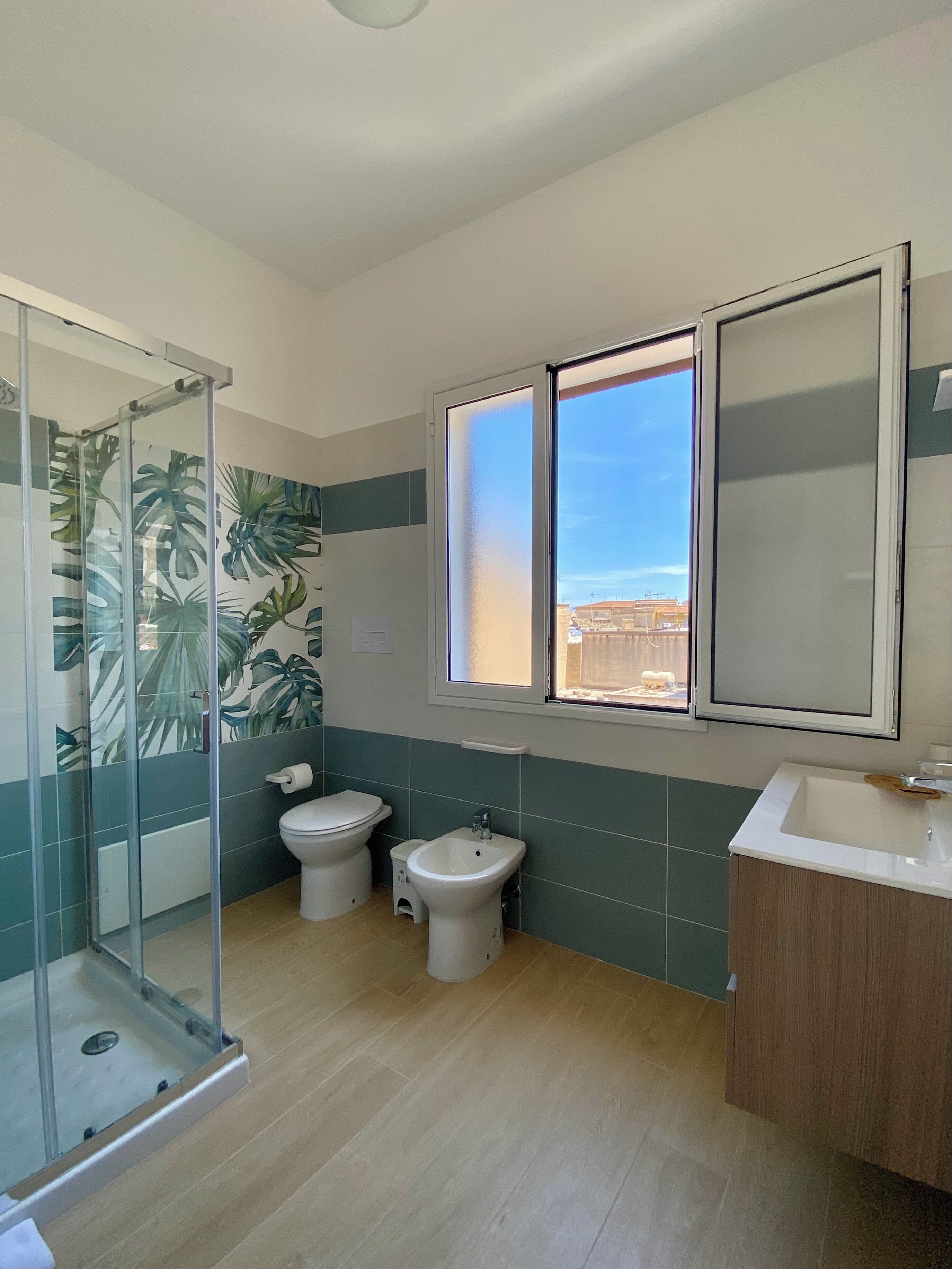 Een badkamer met douche, toilet, wastafel en bidet.