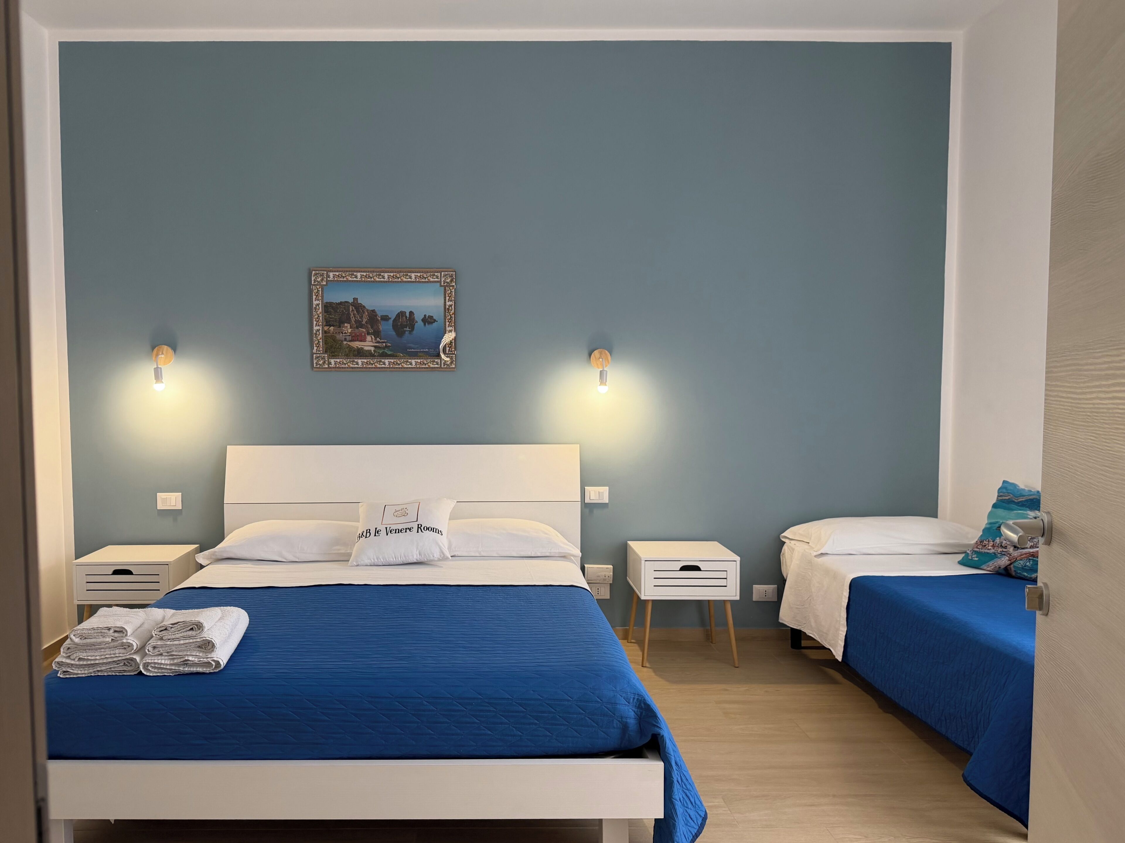 Una habitación de hotel con cama, mesitas de noche, un cuadro colgado en la pared y una ventana.