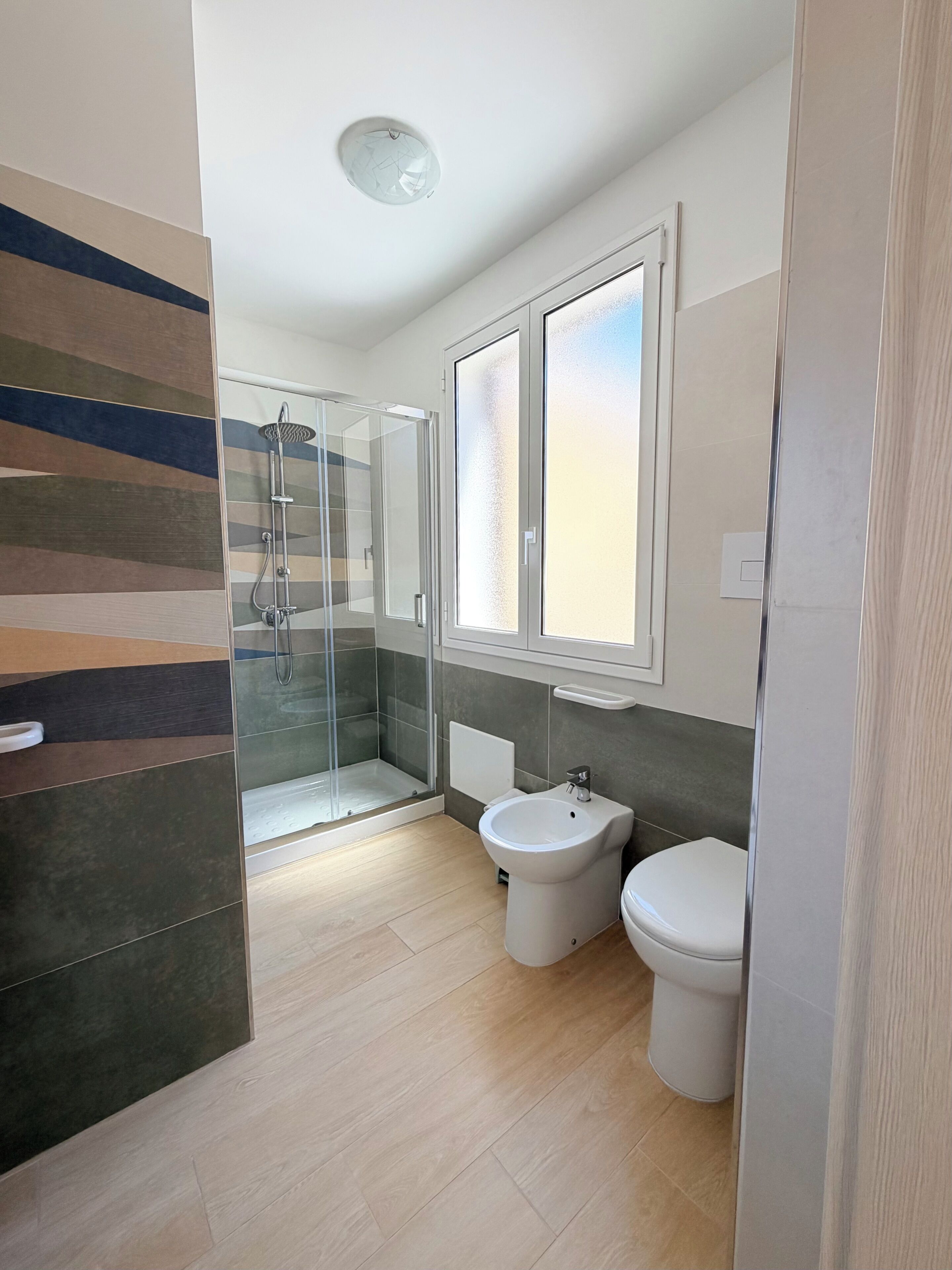 Un baño moderno con cabina de ducha de vidrio, un lavabo blanco y un inodoro.