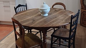 Ein Essbereich mit einem Holztisch, Stühlen, einer weißen Suppenschale und einer hängenden Leuchte.
