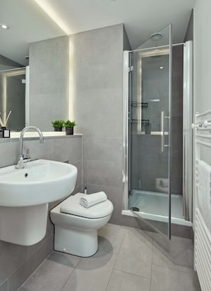 A modern bathroom with a sink, toilet, and glass-enclosed shower. - Trendy Northern Quarter Retreat (Manchester)