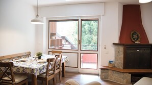Un comedor con una mesa dispuesta para cuatro, sillas de madera y un banco. Hay una chimenea con un marco de piedra y un plato decorativo encima.