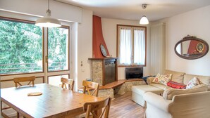 Una sala de estar con chimenea de piedra, televisor, sofá y mesa de comedor con sillas.